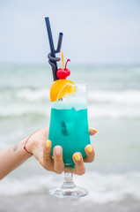 Blue coctail in the glass on the sea background