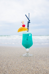 Blue coctail in the glass on the sea background