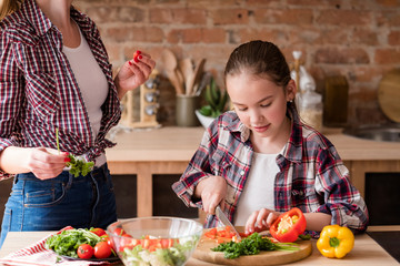 little cook. adolescent girl cutting vegetables and preparing dinner from fresh organic food...