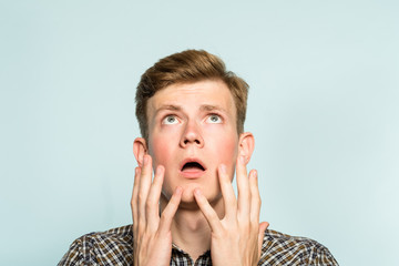 amazed astonished shocked dazed impressed stunned man looking up. portrait of a young guy on light...