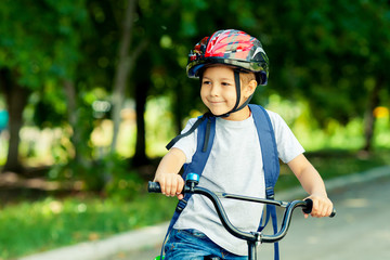 Little boy learns to ride a bike in the park near the home. Portrait of a cute kid on bicycle....