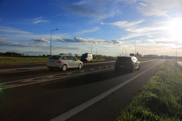 Samochody osobowe i policyjny radiowóz na drodze ekspresowej w promieniach zachodzącego słońca.