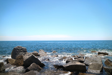 Picture of  a sea and small rocks/stones in front, sunny summer day and blue sky in Portimao, Portugal.
