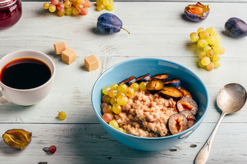 Porridge with plum, grapes and cup of coffee