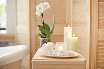 Fototapeta na wymiar set for spa procedure with towel for bathroom procedures, burning candles and flowers.