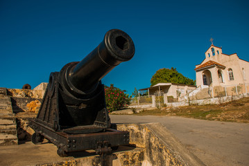 Gun at the entrance to the fortress and the Catholic Church. Old Fortress Fortaleza de Jagua. Cuba, Cienfuegos.