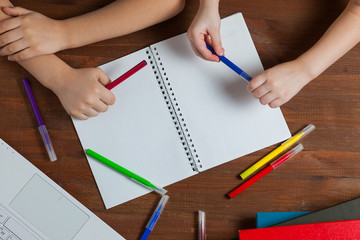 Children do homework at the table. Kids draws on a blank sheet of paper. Preschoolers do homework together. Boy and girl writing a letter.