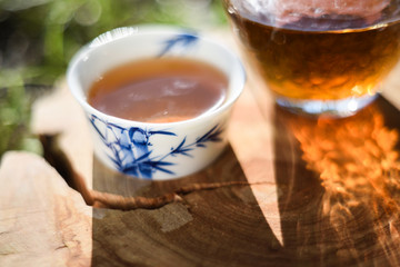 Cups of Chinese black tea on wood slab in bright sun close up copyspace