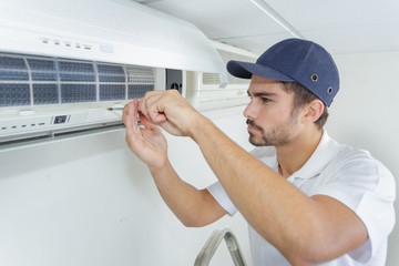 portrait of mid-adult male technician repairing air conditioner