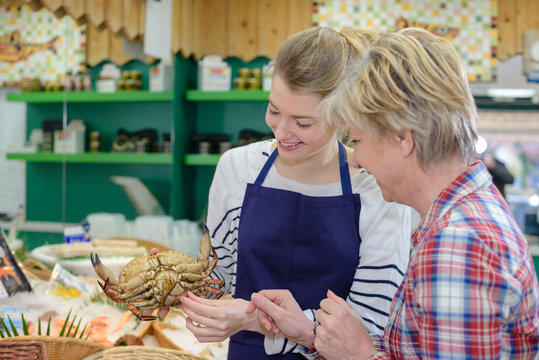 female fishmonger showing crab to customer