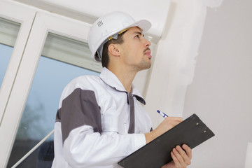 building surveyor writing on his clipboard on a construction site