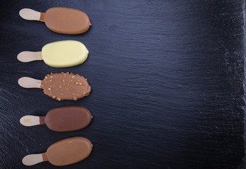 Obraz na płótnie Canvas Ice cream on stick covered with chocolate on black