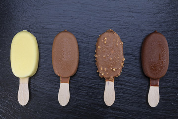 Ice cream on stick covered with chocolate on black slate