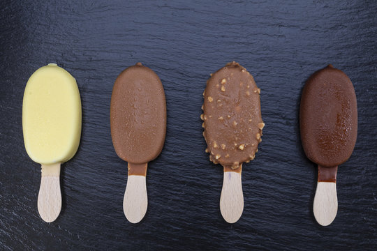 Ice cream on stick covered with chocolate on black slate