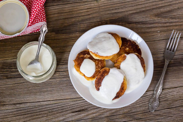 Pancakes with cottage cheese, sour cream in a white plate