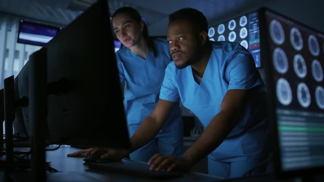 Two Medical Scientists / Neurologists, Talking and  Working on a Personal Computer in Modern Laboratory. Research Scientists Making New Discoveries. Shot on RED EPIC-W 8K Helium Cinema Camera.