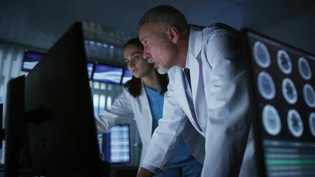 Two Medical Scientists / Neurologists, Talking and  Working on a Personal Computer in Modern Laboratory. Research Scientists Making New Discoveries. Shot on RED EPIC-W 8K Helium Cinema Camera.