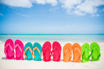 colorful flip flop on sandy beach, green sea and blue sky background for summer holiday and...