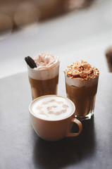 Milkshake macchiato overshake cappuccino on a wooden table in a coffee house. Cups of coffee on wooden background Trendy food concept.