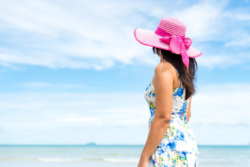 Beautiful woman wearing hat beach and sunglasses stand on hands over sandy beach, green sea and blue sky background for summer holiday and vacation concept.