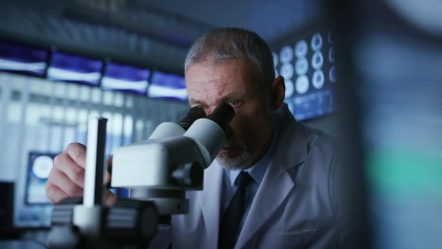 Senior Medical Research Scientist Looking under the Microscope in the Laboratory. Neurologist Solving Puzzles of the Mind and Brain. Shot on RED EPIC-W 8K Helium Cinema Camera.