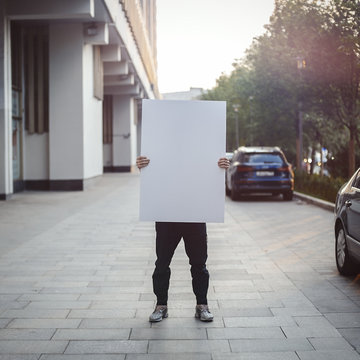 Young attractive man holding blank canvas at the street.