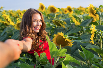 Beautiful young woman holding hands in a sunflower field