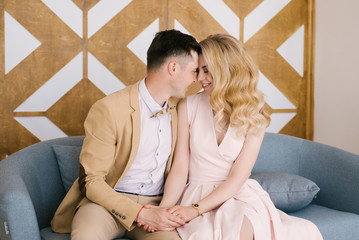 Beautiful loving young couple at home in a beautiful interior and elegant outfits look at each other
