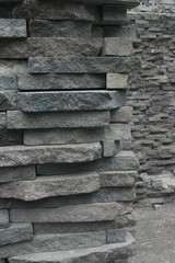 Wall of thinly layered stone with background of the wall continuing for depth and scale 