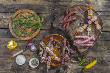 bbq party fest Assortment various barbecue raw food meat, on plates wooden cutting board and grid on an old brown board background