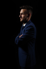 young man on a black background in a suit / hands crossed