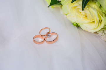Gold wedding rings near rosebud, closeup