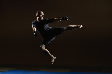 Fototapeta na wymiar A concentrated athlete beats a kick in a jump