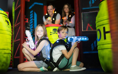 Boy and girl sitting back to back with laser pistols