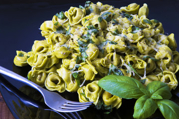 tortellini pasta dish with melted cheese and basil leaf