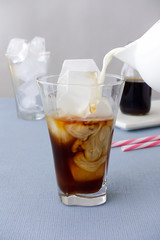 Milk being poured into a glass with cold brew coffee