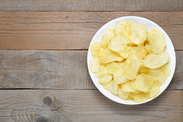 Potato chips in bowl on wooden table