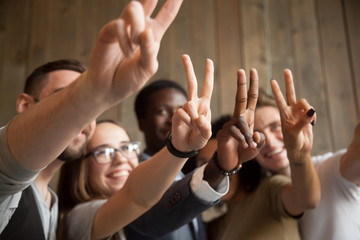 Close up of smiling multiracial people showing V sign making group picture, spending time, having...