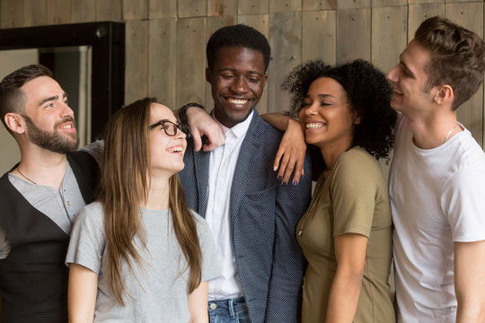 Happy multiracial millennial friends posing for picture at friendly meeting in coffeeshop, smiling diverse students standing laughing at funny joke, having fun together in cafe. Ethnicity concept