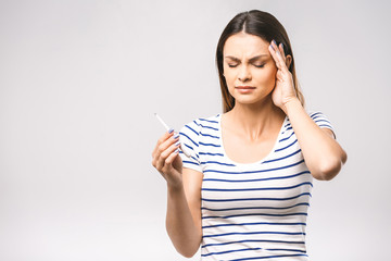 Portrait of a worried young beautiful woman checking her temperature. White background, flu.