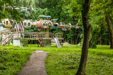 Fototapeta na wymiar deserted poor old dirty and rusty carousel in outdoor green summer park environment from county of onetime USSR