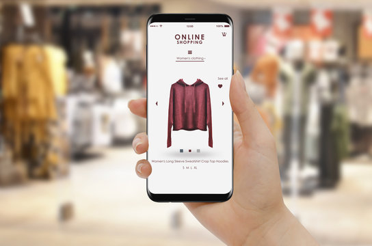 Online shopping with smartphone, clothing store in background