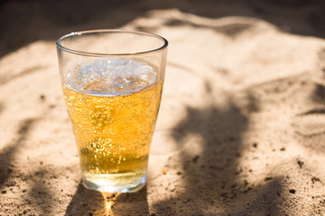 a glass of Cold beer on the beach sand
