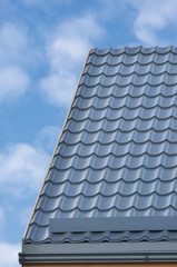 Fototapeta na wymiar Grey Steel Tile Roof Texture Background, Gray Tiled Roofing. Large Detailed Vertical Closeup, Modern Residential House Rooftop Tiles Detail Textured Pattern. Bright Sunny Sky Summer Cloudscape Clouds