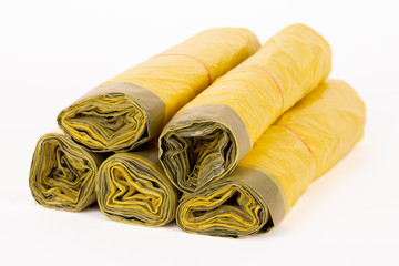 Rolls of yellow trash bags on white background