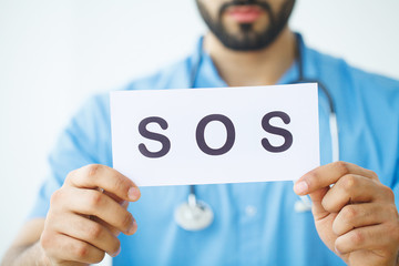 Health Care. Doctor Holding a Card With Symbol SOS, Medical Concept