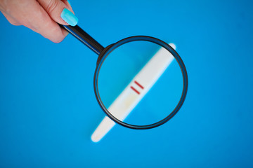 Pregnancy test with a positive result lying on a blue background.