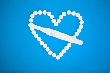 Pregnancy planning concep. Pregnancy test positive with two stripes and contraceptive pill on blue background.