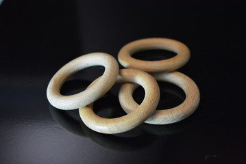 On a black glossy background there are four wooden rings of brown color with reflection