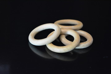 On a black glossy background there are four wooden rings of brown color with reflection